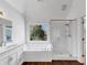 Bright main bathroom featuring a shower, a bathtub with jets, and a vanity with a large mirror at , Suwanee, GA 30024