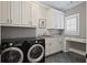 Modern laundry room with black washer and dryer, white cabinetry, and a workstation at 5119 Greythorne Ln, Marietta, GA 30068