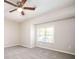 Bright bedroom featuring plush carpeting, neutral paint, a ceiling fan, and a sunlit window at 5474 Post Road Pass, Stone Mountain, GA 30088