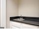 Close-up view of a wet bar with white cabinets and a black countertop at 5474 Post Road Pass, Stone Mountain, GA 30088