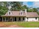 Inviting gray home featuring a covered front porch, well-manicured lawn, and mature trees at 60 Valley Rd, Covington, GA 30016