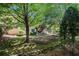 Shady backyard featuring a stone retaining wall and mature trees in a tranquil setting at 1600 Heritage Trl, Roswell, GA 30075