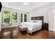 Bright bedroom features hardwood floors, wood-look accent wall, large windows, and a comfortable bed at 1600 Heritage Trl, Roswell, GA 30075