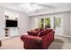 Cozy living room with a comfortable red sofa, built-in shelving, and natural light from the windows at 1600 Heritage Trl, Roswell, GA 30075