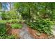 Well-maintained front yard with a stone pathway, lush greenery, and decorative potted plants at 4649 Dahlia Dr, Pine Lake, GA 30072