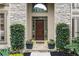 Inviting front entrance with a stone facade, decorative plants, and a dark wood front door at 7059 Hunters Rdg, Woodstock, GA 30189