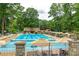 Large outdoor pool with lounge chairs, umbrellas, and a stone fence in a park-like setting at 894 Nottingham Dr, Avondale Estates, GA 30002