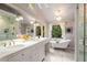 Elegant bathroom featuring a double vanity, soaking tub under a window, chandeliers, and marble floors at 1041 Standard Ne Dr, Brookhaven, GA 30319