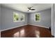 Gray bedroom with hardwood floors, three windows that provide ample natural light, and a modern ceiling fan at 128 Reynolds Bridge Rd, Kingston, GA 30145