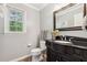 Powder room with granite counters, dark wood vanity, and decorative mirror at 1300 Sever Woods Dr, Lawrenceville, GA 30043