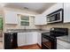 Bright kitchen with white cabinetry, black appliances, and hardwood flooring at 115 Manx Dr, Grantville, GA 30220