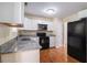 Well-lit kitchen featuring white cabinets, granite countertops, and black appliances at 115 Manx Dr, Grantville, GA 30220