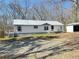 Charming single-story home with white siding, metal roof and a quaint porch, nestled in a wooded setting at 7301 Staton Se Pl, Acworth, GA 30102