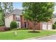 Traditional brick front exterior features a three-car garage, manicured lawn and mature shade tree at 2500 Madison Commons, Atlanta, GA 30360
