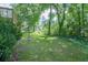 Large grassy backyard featuring mature shade trees and the corner of a wooden deck at 2668 Kings Way, Lawrenceville, GA 30044