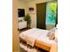 Staged bedroom featuring a bed, dresser, plant, artwork, and window with green view at 19302 Waldrop Cv, Decatur, GA 30034