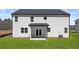 A view of the home's backyard, featuring a grassy lawn and a simple covered patio accessible through double doors at 1950 Van Allen Ct, Dacula, GA 30019