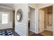 Hallway view showcases white wainscoting, artful mirror, leading to a full bathroom with tub and shower at 655 Blackshear Trl, Temple, GA 30179