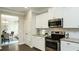 Modern kitchen with stainless steel oven, granite countertops, white cabinets, and view to the dining area at 655 Blackshear Trl, Temple, GA 30179