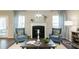 Cozy living room with a fireplace, blue armchairs, and large windows offering ample natural light at 655 Blackshear Trl, Temple, GA 30179