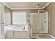 Bright bathroom featuring a soaking tub with window and a glass-enclosed shower at 4213 Bretdale Nw Run, Kennesaw, GA 30152