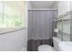 Cozy bathroom featuring a shower with striped curtain, tiled walls, and shelf for added storage at 4236 Beaver Ruin Nw Ct, Lilburn, GA 30047