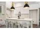 White kitchen island with marble countertop, pendant lights, stainless steel stools, and hardwood flooring at 481 Glenwood Se Ave, Atlanta, GA 30312