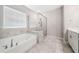 Bright bathroom featuring tub under window and glass enclosed shower, showcasing modern fixtures and neutral tile at 495 Duval Dr, Alpharetta, GA 30009