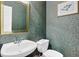 Small bathroom with a white sink, toilet, decorative mirror, and wallpaper at 283 Heron Lake Ct, Lawrenceville, GA 30043
