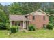 Charming two-story brick home featuring a covered front porch and red shutters surrounded by lush greenery at 1576 King Mill Rd, Mcdonough, GA 30252