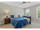 Comfortable bedroom featuring a blue bedspread, ceiling fan, and natural light from large windows at 235 Foxley Way, Roswell, GA 30075