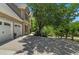 Charming front exterior showing a large tree, three-car garage, and driveway at 235 Foxley Way, Roswell, GA 30075
