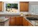 Close-up of kitchen featuring granite countertops, wood cabinets, gas cooktop, and window overlooking the yard at 235 Foxley Way, Roswell, GA 30075