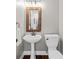 Charming powder room featuring pedestal sink, rustic mirror, and wood-look flooring at 235 Foxley Way, Roswell, GA 30075