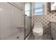 Bright bathroom featuring a tiled shower and window, complemented by patterned wallpaper at 4137 Wellington Hills Ln, Snellville, GA 30039
