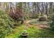 Lush backyard garden featuring mature trees, ferns, ground cover and a decorative fountain, offering a tranquil setting at 6795 Brandon Mill Rd, Atlanta, GA 30328