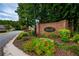 Entrance to The Enclave at Saddle Creek, featuring lush landscaping and brick signage at 8675 Hope Vine, Roswell, GA 30076