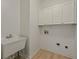 Laundry room featuring white walls, upper cabinets, wood floors, and laundry sink at 8675 Hope Vine, Roswell, GA 30076