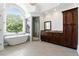 Bright bathroom featuring a soaking tub, a walk-in shower, and elegant finishes bathed in natural light from a large arched window at 4011 Charrwood Trce, Marietta, GA 30062