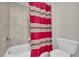 Bathroom with a red patterned shower curtain, white toilet, and a tiled tub surround at 1213 Fairwinds Dr, Loganville, GA 30052