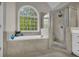 The bathroom features a large tub beneath a large arched window and a glass-enclosed shower at 1213 Fairwinds Dr, Loganville, GA 30052