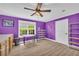 Bedroom featuring wood flooring, a ceiling fan, purple painted walls, and a bright window at 1213 Fairwinds Dr, Loganville, GA 30052