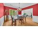 Dining room with hardwood floors, bright red walls, wainscoting, decorative chandelier and large windows at 1213 Fairwinds Dr, Loganville, GA 30052