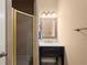 Well-lit bathroom featuring a shower with gold trim, a vanity with dark wood drawers, and a framed mirror at 580 Washington Way, Cumming, GA 30040