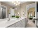 Well-lit bathroom features double sinks with white cabinetry, an oversized mirror, and an entry to the bedroom at 580 Washington Way, Cumming, GA 30040