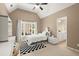 Cozy bedroom features a vaulted ceiling, a black and white rug, and a view into the ensuite bathroom at 580 Washington Way, Cumming, GA 30040