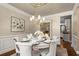 Formal dining room with elegant chandelier, wainscoting, and views to the kitchen at 580 Washington Way, Cumming, GA 30040