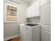 The laundry room features white cabinets and modern washer and dryer machines at 580 Washington Way, Cumming, GA 30040