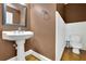 Cozy powder room featuring a modern pedestal sink, wood floors, and white paneling at 10765 Arlington Pt, Alpharetta, GA 30022