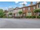 Street view of a row of brick townhomes with manicured lawns and mature trees at 10765 Arlington Pt, Alpharetta, GA 30022